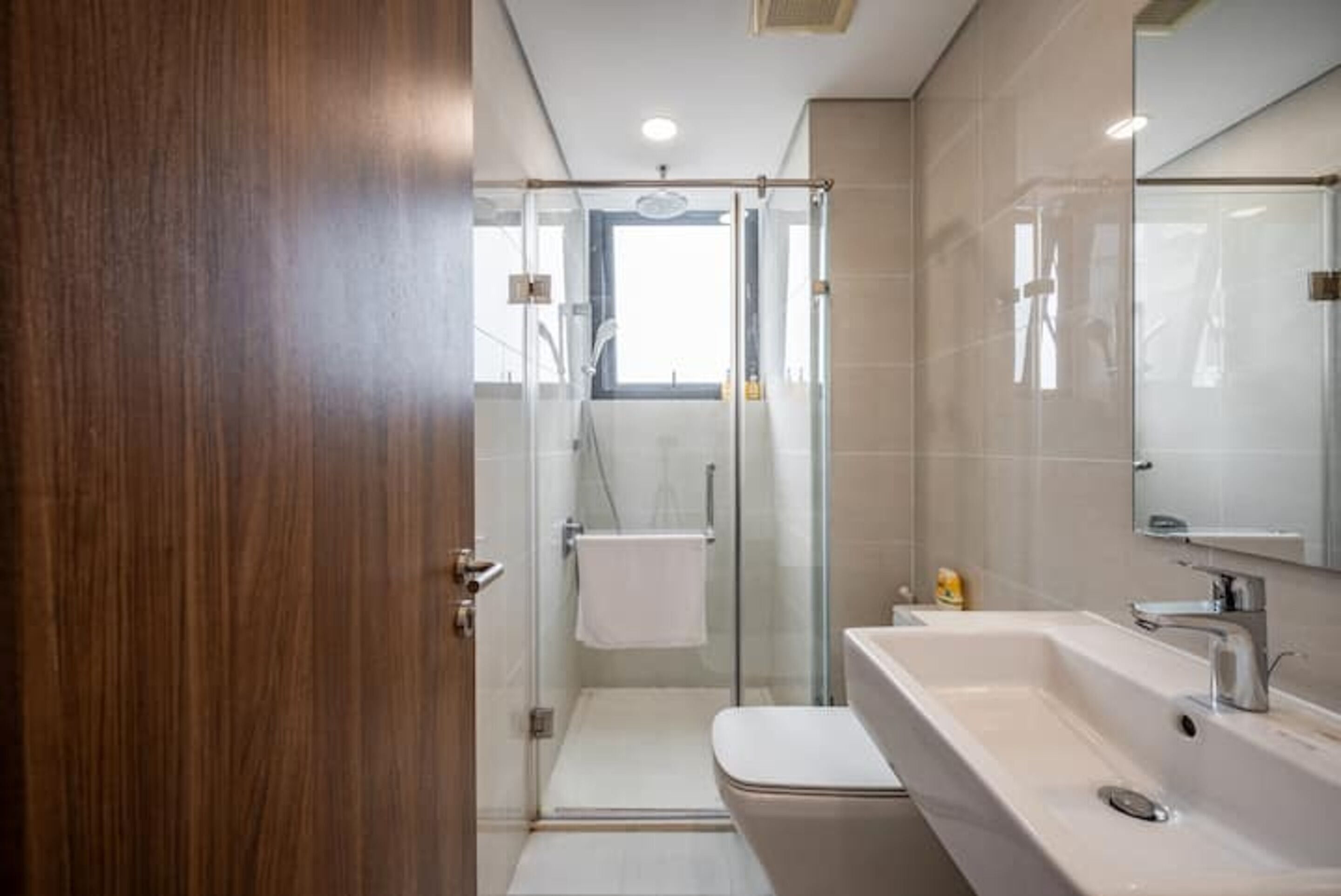 Une salle de bain moderne avec une douche à l’italienne en verre, un lavabo blanc et un grand miroir.