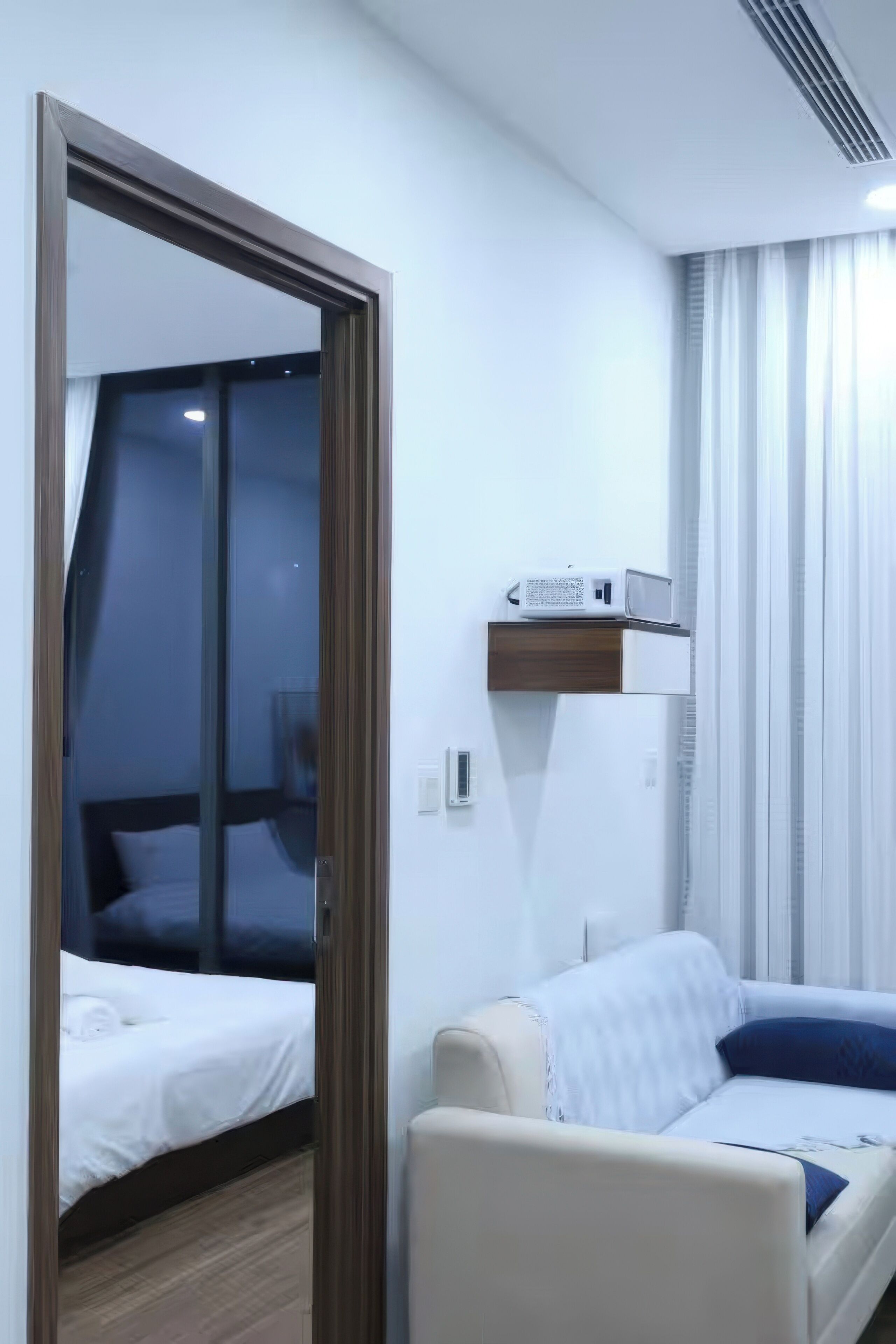 Une chambre d’hôtel équipée d’un lit, d’un canapé, d’un miroir et d’un climatiseur fixé au plafond.
