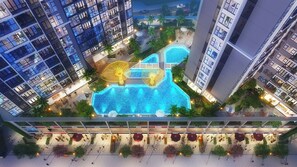 Vue aérienne d’un hôtel moderne composé de plusieurs immeubles de grande hauteur, avec une piscine centrale et des espaces de détente en plein air.