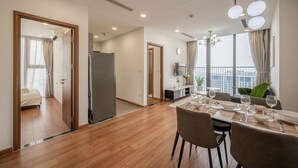 Una habitación de hotel moderna con suelo de madera, un área de comedor con mesa puesta para cuatro personas y un balcón con vistas.