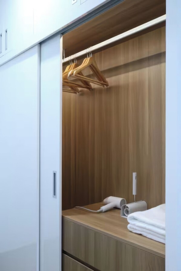 Un dressing accessible sans porte, avec des panneaux en bois, une tringle à vêtements et une serviette soigneusement pliée posée sur le comptoir.