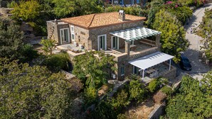 Una villa de piedra con techo de tejas, varios balcones y una zona de estar exterior cubierta.