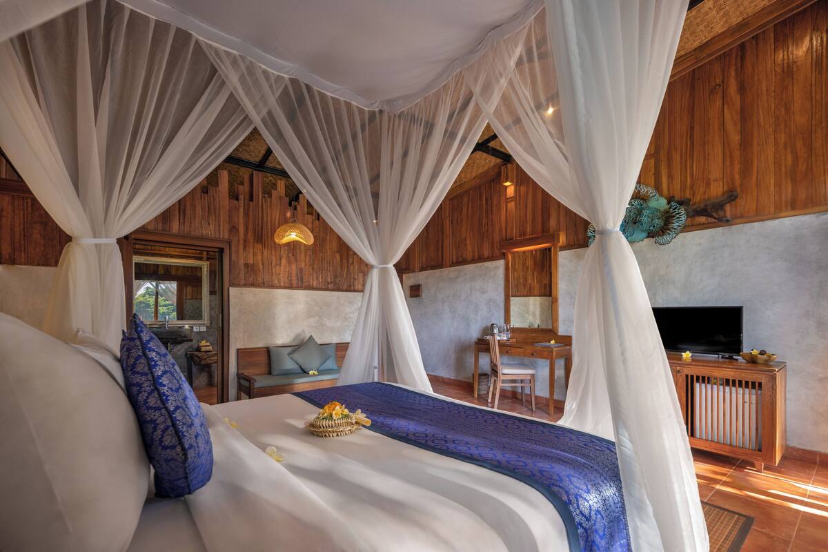 Ein Schlafzimmer mit Baldachinbett, Schreibtisch und Fernseher.