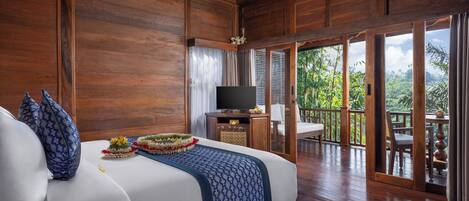 Habitación de madera con cama, televisión y balcón con vistas a la vegetación.