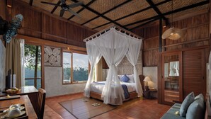 A room with a four-poster bed, wooden walls, a ceiling fan, and large windows offering a view of the outdoors. - Sacred Valley by GenuineHost (Sebatu)