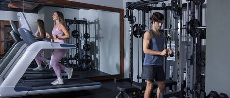 Una palestra con tapis roulant, macchinari per pesi e manubri.