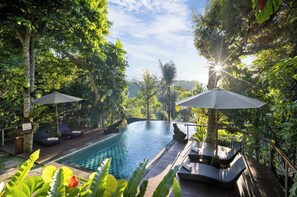 A serene outdoor pool area with lounge chairs and umbrellas, surrounded by lush greenery. - Sacred Valley by GenuineHost (Sebatu)