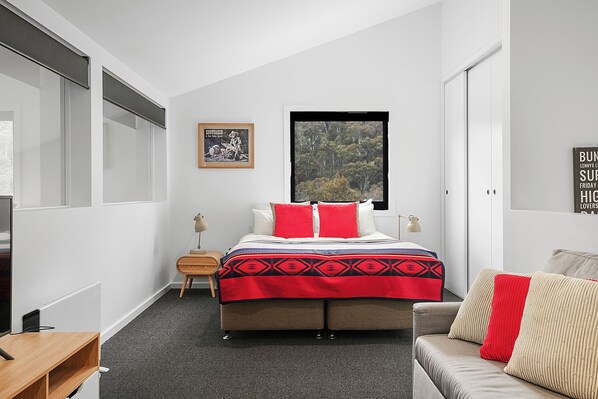 A bedroom with a bed, a window, a bedside table, and a couch. - Snowbound 2 - Family Ski Chalet, 5 minute walk to the slopes (Thredbo)