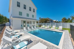 Ein Schwimmbecken mit Liegestühlen und einer überdachten Terrasse.