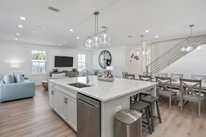 A modern kitchen with a central island, stainless steel appliances, and a dining area with wooden chairs.
