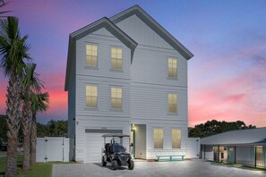 A two-story building with a garage, a covered parking area, and a bench.