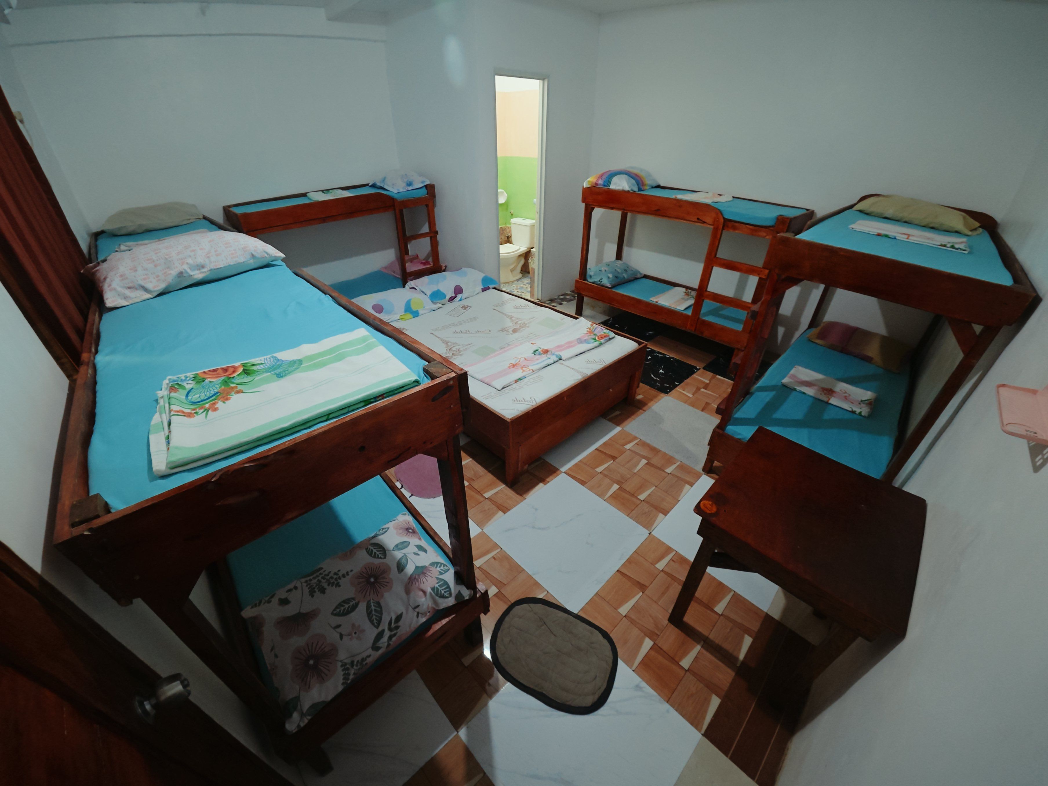 Quarto tipo dormitório com beliches, uma pequena mesa e uma cadeira.