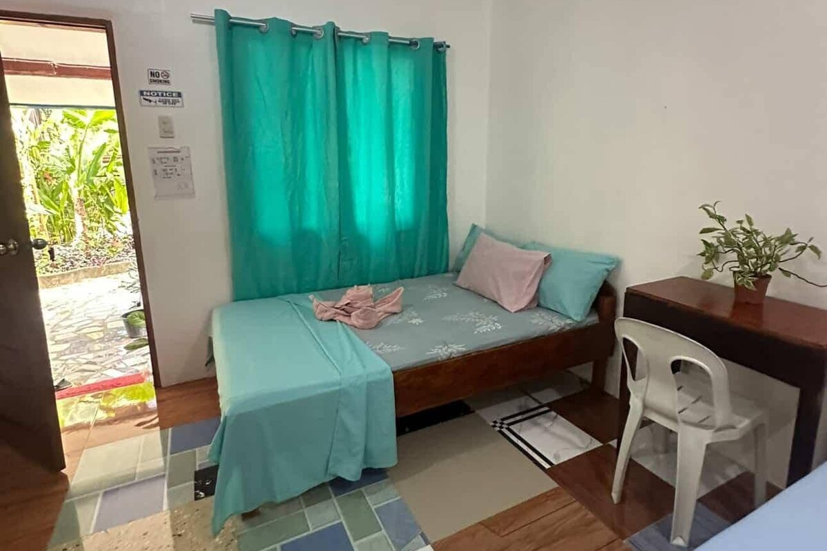 Un petit logement composé d’une seule pièce, comprenant un lit, un bureau et une chaise.