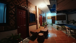 A hallway with a wooden floor, a dining area with a table and chairs, and a door with a patterned design. - moonlight inn catangnan  (General Luna)