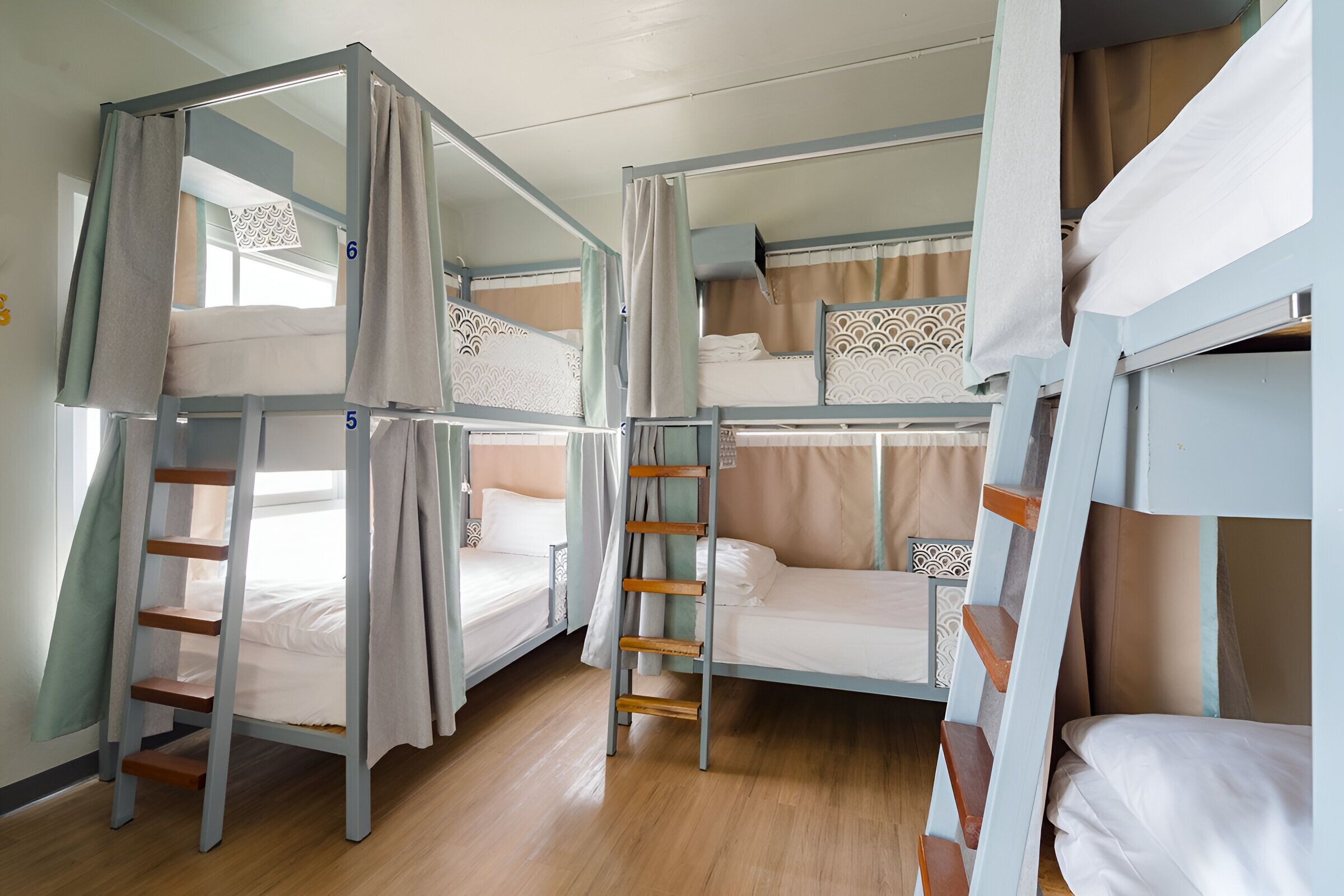 Un dormitorio con literas, escaleras de madera y almohadas estampadas.