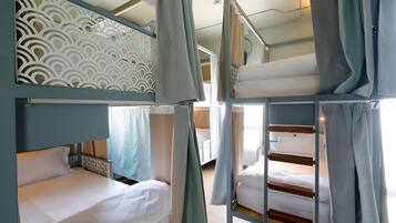 A bunk bed room with a patterned headboard, curtains, and a wooden floor.
