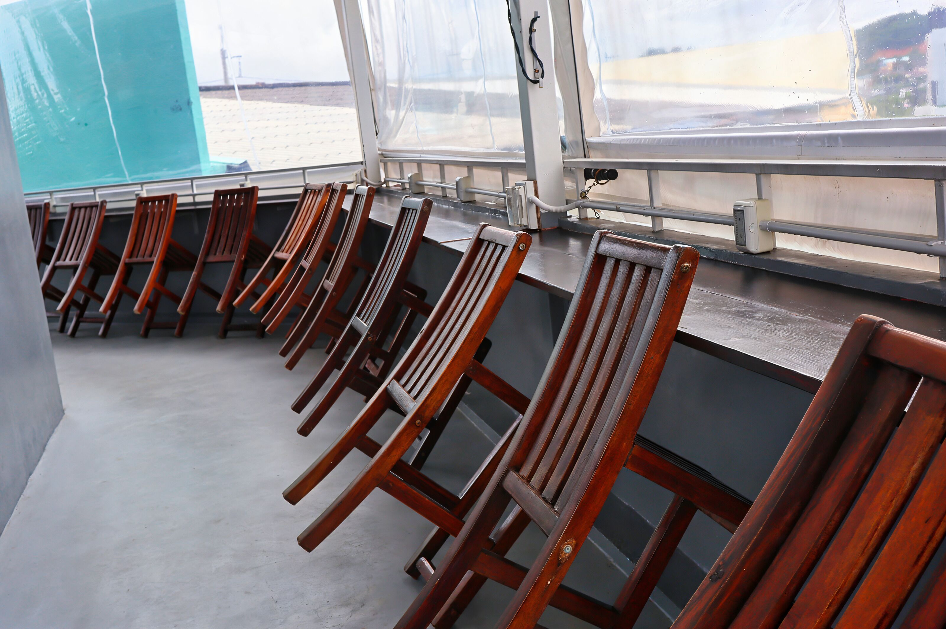 Rijen houten stoelen staan op een balkon met uitzicht op het strand.