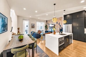 A modern kitchen with a central island, black cabinetry, and stainless steel appliances.