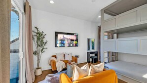 A modern living room with a sofa, a coffee table, a TV, and a potted plant. - Nashville escape with hot tub, karaoke lounge & makeup bar, sleeps 12 (Nashville)