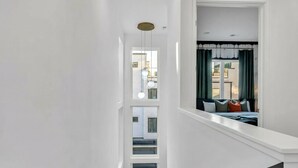 A modern interior with a staircase leading to a bedroom. The room features a large window with curtains, a bed with pillows, and a view of the outside. - Nashville escape with hot tub, karaoke lounge & makeup bar, sleeps 12 (Nashville)