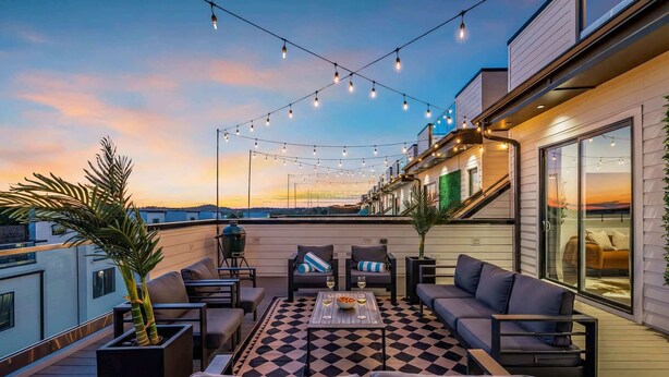 A rooftop terrace with outdoor seating, string lights, and a view of the sunset. - Nashville escape with hot tub, karaoke lounge & makeup bar, sleeps 12 (Nashville)