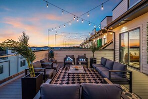 A rooftop terrace with outdoor seating, string lights, and a view of the sunset. - Nashville house, rooftop hot tub, karaoke & luxury lounges, sleeps 12 (Nashville)