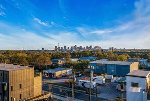 A city skyline with modern buildings, a parking lot with trucks, and a clear blue sky.