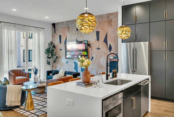 A modern kitchen with a central island, stainless steel appliances, and pendant lighting.