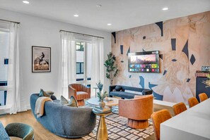 A modern living room with a sofa, armchairs, a coffee table, and a TV mounted on the wall. - Nashville house, rooftop hot tub, karaoke & luxury lounges, sleeps 12 (Nashville)