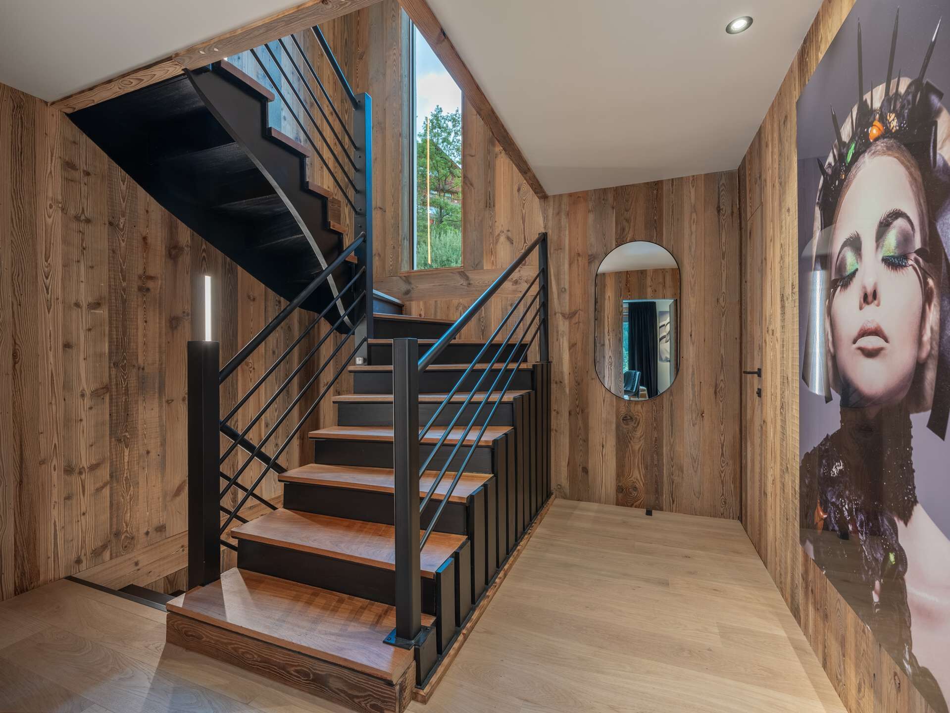 A wooden interior with a staircase, a mirror, and a large wall mural.