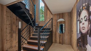 A wooden interior with a staircase, a mirror, and a large wall mural.