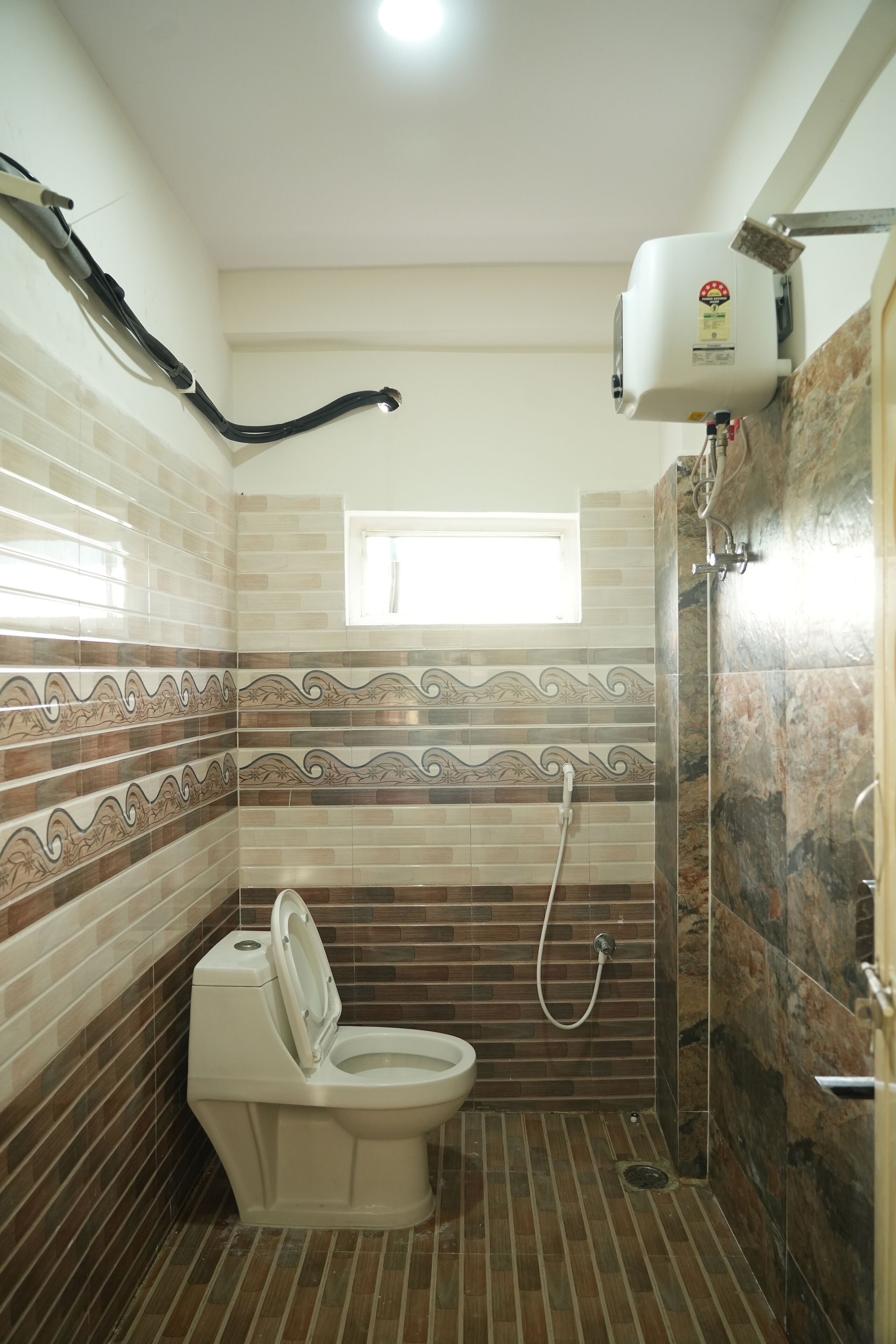 A bathroom with a toilet, shower, and a window.