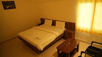 Quarto de hotel com cama, mesa de cabeceira, cadeira e um quadro na parede.