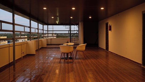 Un vaste espace intérieur doté d’un plancher en bois, de grandes fenêtres et d’un escalier menant à un niveau supérieur.