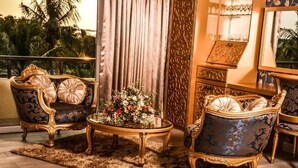 A luxurious room with ornate furniture, a decorative mirror, and a view of palm trees.