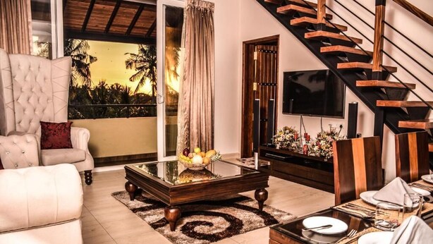 A living room with a sofa, coffee table, and a dining area set for a meal.