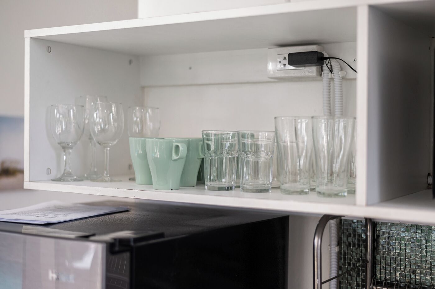 A kitchen cabinet with various glassware, including wine glasses and tumblers.