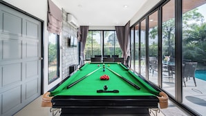 A pool table in a room with large windows, a door, and a stone wall. - AnB Loft 1 poolvilla close Jomtian beach (Bang Lamung)