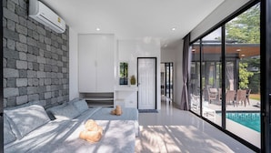 A modern living room with a stone wall, a sofa, a window, and a pool view. - AnB Loft 1 poolvilla close Jomtian beach (Bang Lamung)
