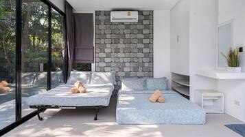 A modern bedroom with two beds, a stone wall, an air conditioning unit, and a view of trees.