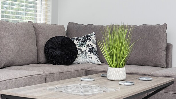 Ein stilvolles Wohnzimmer mit einem grauen Sofa, einem Holztisch und Zierkissen.
