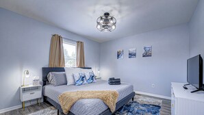 Ein Schlafzimmer mit Bett, Nachttischen, einem Fernseher und Bildern an der Wand.