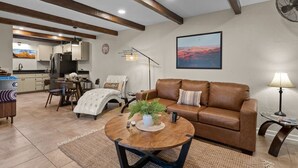 A modern living room with a brown leather sofa, a round coffee table, and a dining area with a table and chairs. - Chic Zen-Inspired Oasis w/ Patio & Red Rock Views (Sedona)