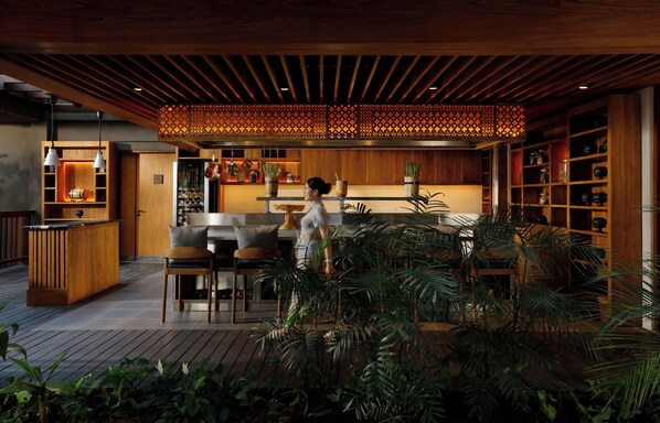 A modern kitchen with wooden cabinets, a bar area, and a dining space.