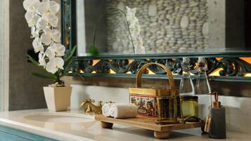 A bathroom vanity with a mirror, a potted orchid, a towel, a decorative tray with toiletries, and a stone soap dispenser.