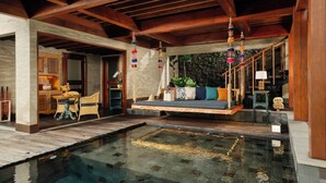 A spacious indoor pool area with a wooden ceiling and a seating area with cushions.