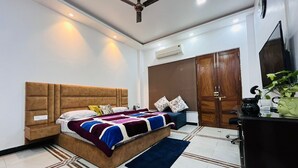 Quarto com cama, ventoinha no teto, ar condicionado, guarda-roupa e secretária com chaleira.