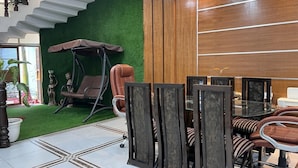 Um interior moderno com parede verde, painéis de madeira, uma cadeira balanço e um espaço de jantar com cadeiras e mesa.