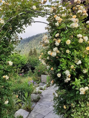 A garden pathway with a variety of flowering plants and a stone wall. - Vacation Apartment (2) 29 m² for up to 2 people (Reit im Winkl)