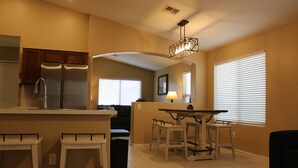 Une cuisine moderne dotée d’un îlot central, de tabourets de bar et d’un coin repas avec une table et des chaises.